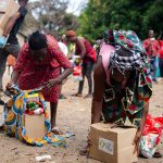People collecting relief supplies in a community outdoor setting.